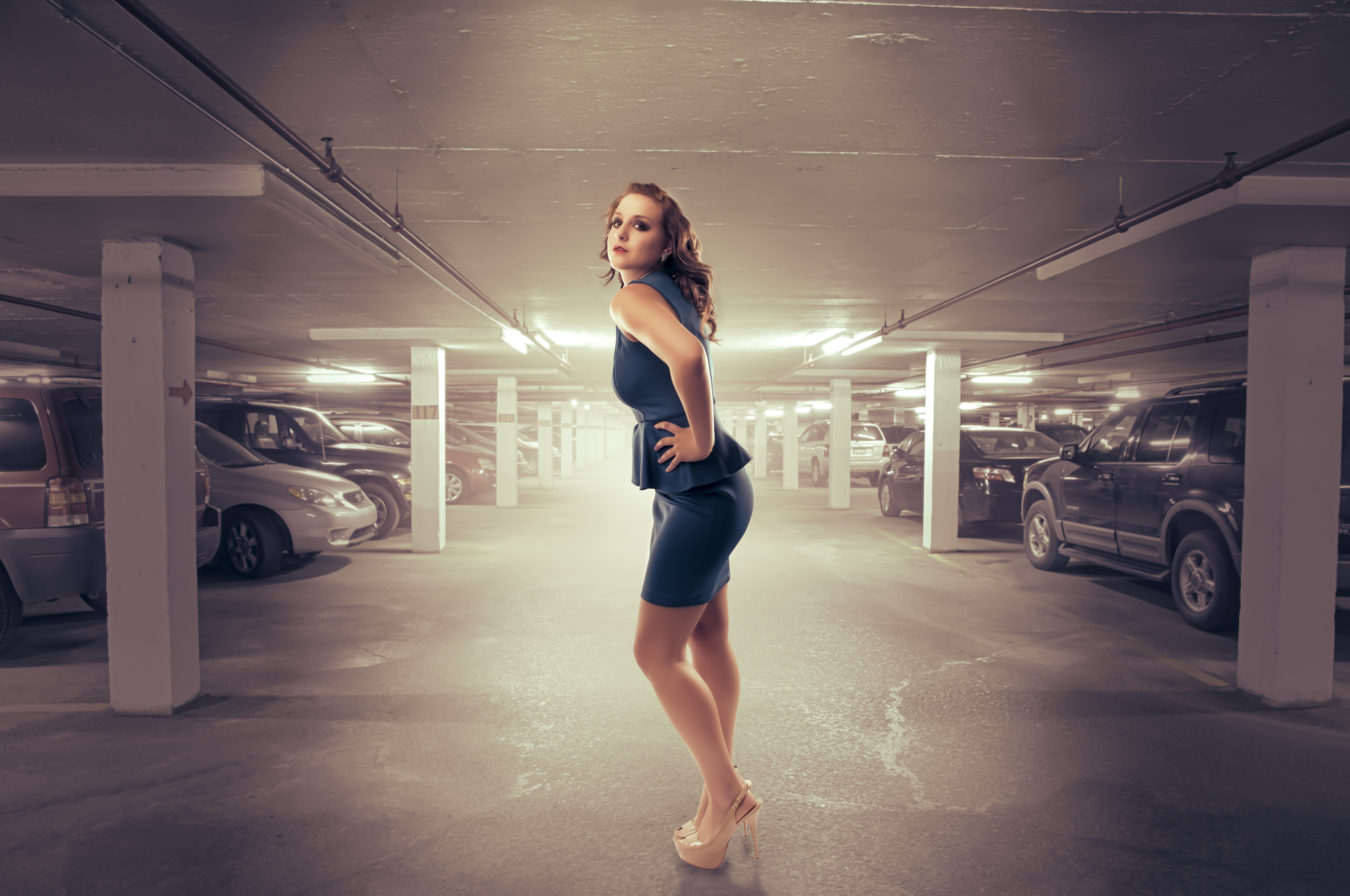 Woman poses in parking garage. 